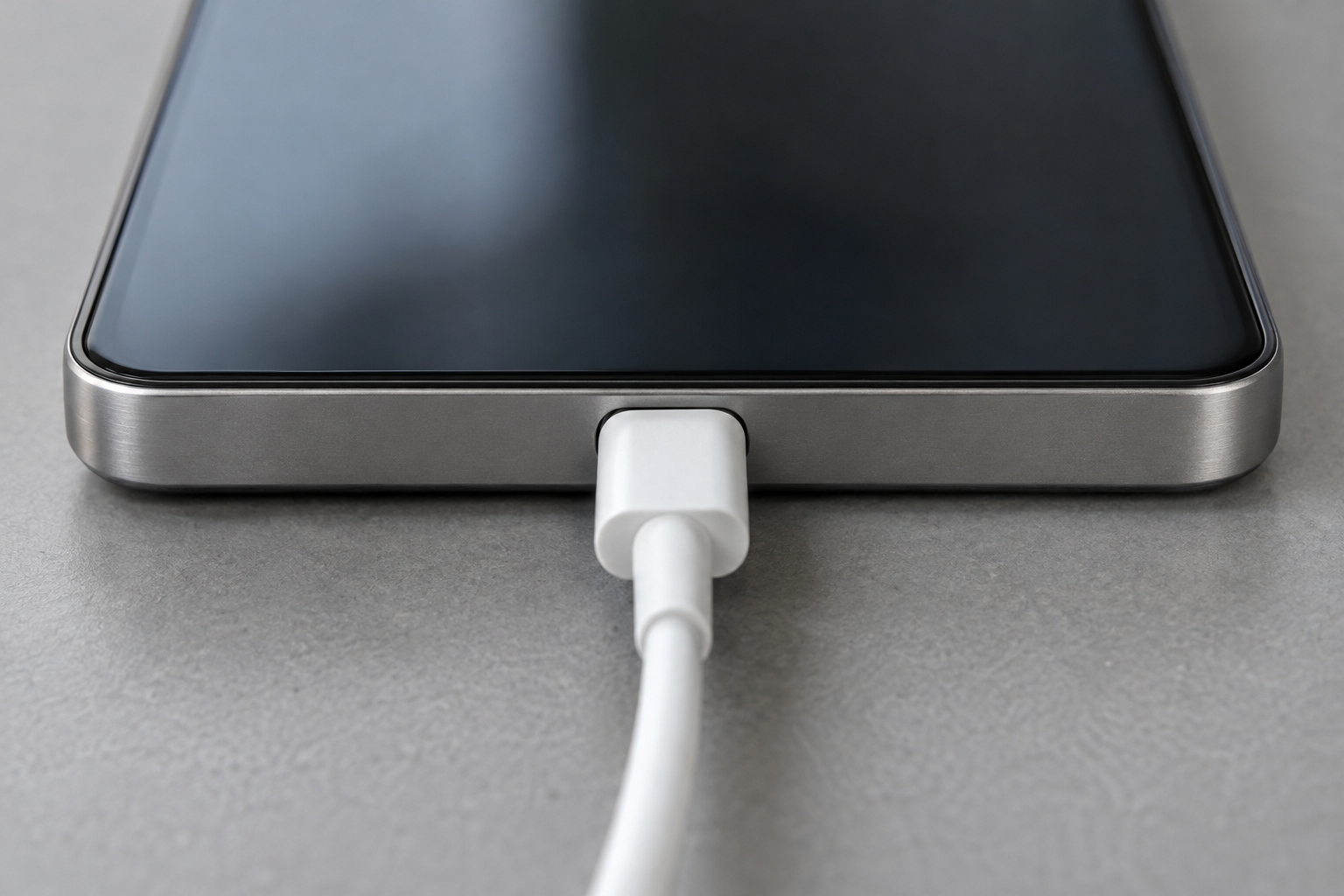 Close view of a plain white USB-C cable seated in the single centered port on the blank bottom edge of a generic Android phone.